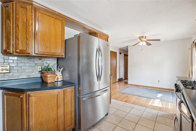 918 29th St NW, Cedar Rapids, IA 52405 - kitchen featuring stainless steel appliances, brown cabinets, ceiling fan, dark countertops, and light tile patterned floors