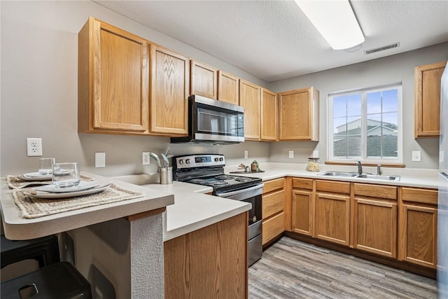 780 Magnolia Ln Unit 4, Marion, IA 52302 - kitchen with appliances with stainless steel finishes, a peninsula, light wood-style floors, a textured ceiling, and light countertops