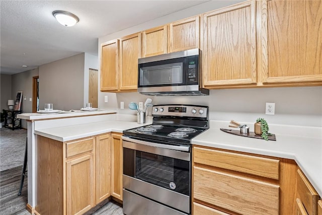 780 Magnolia Ln Unit 4, Marion, IA 52302 - kitchen featuring stainless steel appliances, light brown cabinets, a peninsula, light countertops, and a kitchen breakfast bar