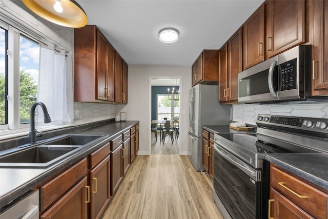 4812 Montclair Dr NW, Cedar Rapids, IA 52405 - kitchen featuring appliances with stainless steel finishes, light wood-style flooring, dark countertops, and decorative backsplash