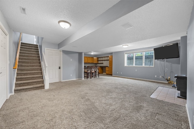 1125 Saint Andrews Dr, North Liberty, IA 52317 - unfurnished living room featuring carpet flooring, stairway, a textured ceiling, a wood stove, and bar