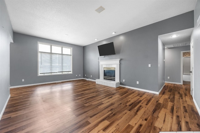 1125 Saint Andrews Dr, North Liberty, IA 52317 - unfurnished living room featuring wood finished floors, a tiled fireplace, a textured ceiling, and recessed lighting