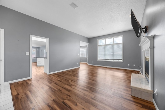 1125 Saint Andrews Dr, North Liberty, IA 52317 - unfurnished living room with wood finished floors, a tile fireplace, and a textured ceiling