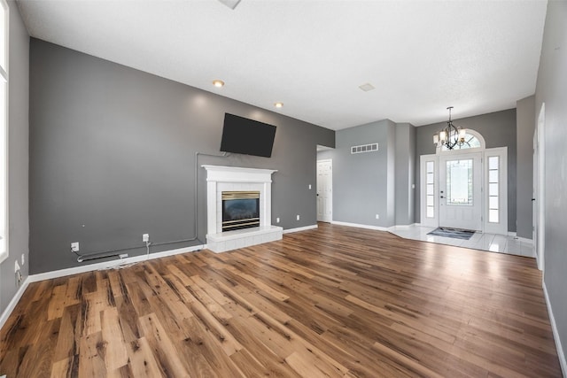1125 Saint Andrews Dr, North Liberty, IA 52317 - unfurnished living room featuring a chandelier, wood finished floors, and a tiled fireplace