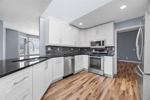 1125 Saint Andrews Dr, North Liberty, IA 52317 - kitchen with stainless steel appliances, light wood-type flooring, tasteful backsplash, white cabinets, and recessed lighting