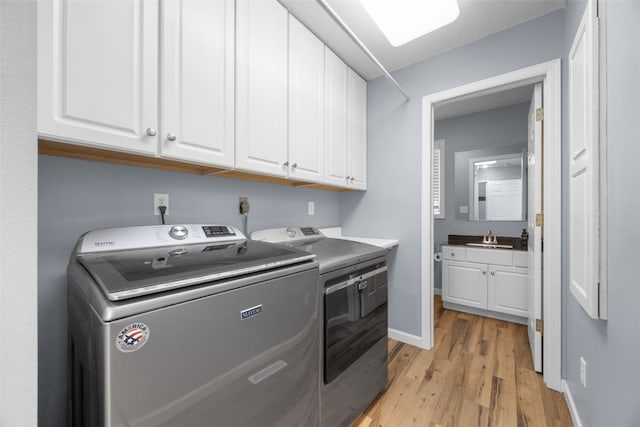 1125 Saint Andrews Dr, North Liberty, IA 52317 - laundry room featuring cabinet space, washer and dryer, and light wood-style floors