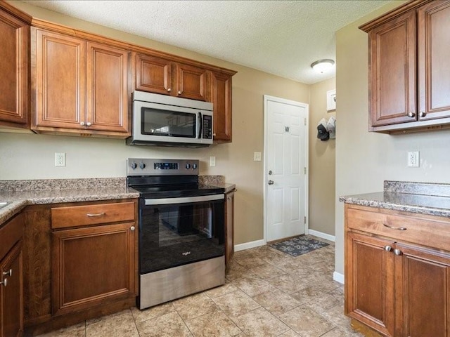 1175 F Ave, Marion, IA 52302 - kitchen featuring stainless steel appliances, brown cabinetry, and a textured ceiling