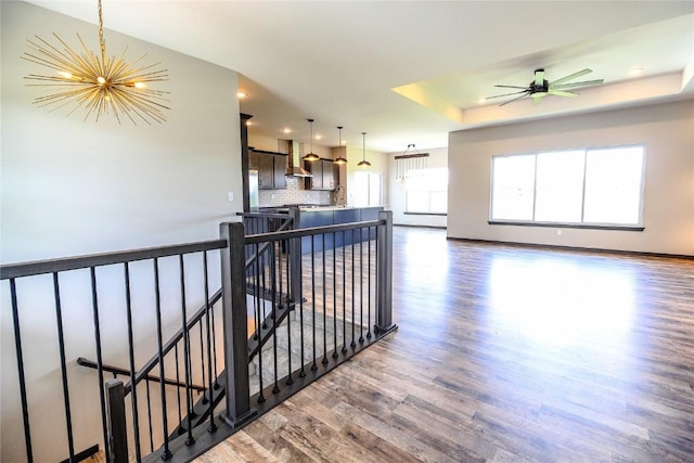 1600 Heartland St, Fairfax, IA 52228 - kitchen featuring a chandelier, wood finished floors, wall chimney range hood, decorative backsplash, and a raised ceiling