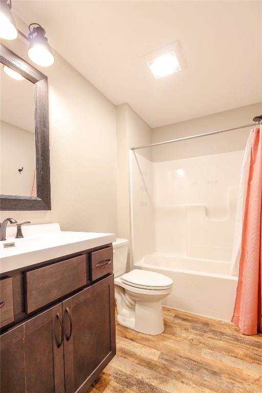 1600 Heartland St, Fairfax, IA 52228 - full bath featuring wood finished floors, vanity, and shower / bath combo with shower curtain