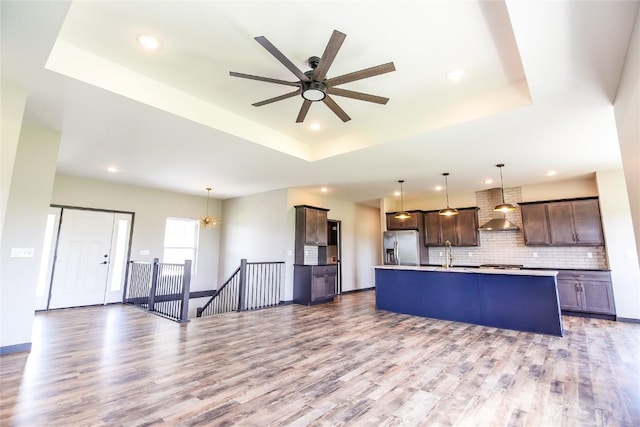 1600 Heartland St, Fairfax, IA 52228 - kitchen with wall chimney exhaust hood, a raised ceiling, appliances with stainless steel finishes, dark brown cabinets, and backsplash