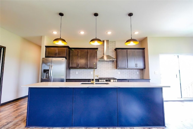 1600 Heartland St, Fairfax, IA 52228 - kitchen with wall chimney range hood, stainless steel fridge, an island with sink, dark brown cabinetry, and decorative backsplash