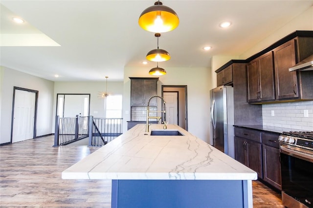 1600 Heartland St, Fairfax, IA 52228 - kitchen with stainless steel appliances, an island with sink, tasteful backsplash, wood finished floors, and dark brown cabinets