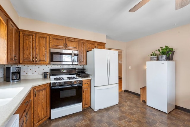 2469 1st St SW, Cedar Rapids, IA 52404 - kitchen featuring white appliances, brown cabinets, tasteful backsplash, light countertops, and a ceiling fan