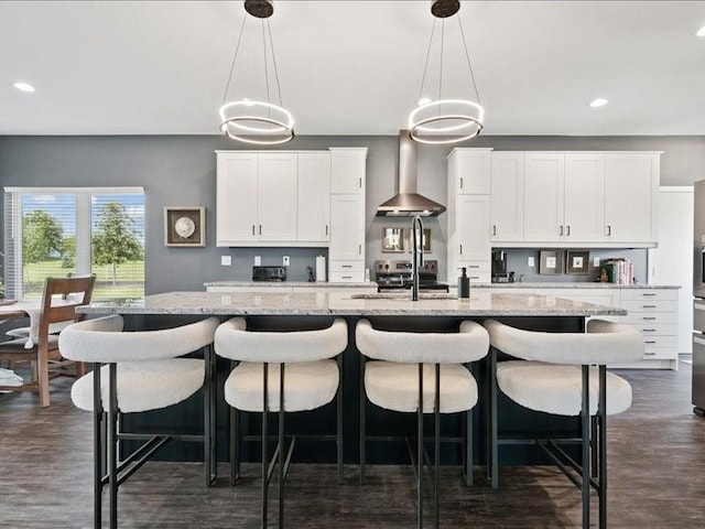 5112 Scenic View Ct SW, Cedar Rapids, IA 52404 - kitchen with wall chimney exhaust hood, a kitchen island with sink, recessed lighting, hanging light fixtures, and white cabinetry