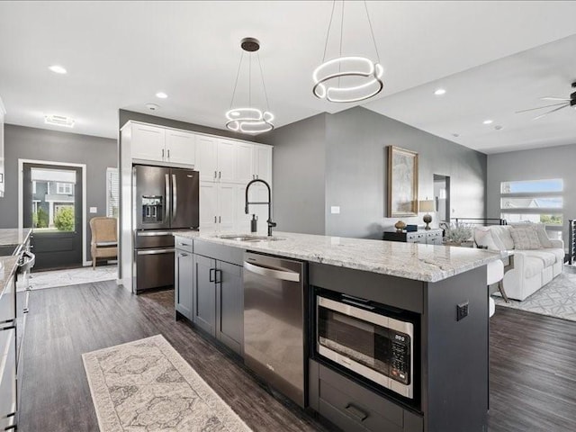 5112 Scenic View Ct SW, Cedar Rapids, IA 52404 - kitchen featuring appliances with stainless steel finishes, light stone counters, white cabinets, open floor plan, and decorative light fixtures