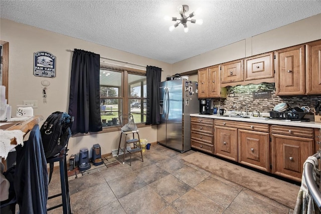 200 Drexel Dr SW, Cedar Rapids, IA 52404 - kitchen featuring stainless steel refrigerator with ice dispenser, light countertops, a textured ceiling, brown cabinetry, and decorative backsplash