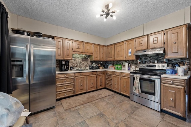 200 Drexel Dr SW, Cedar Rapids, IA 52404 - kitchen with stainless steel appliances, under cabinet range hood, light countertops, a textured ceiling, and decorative backsplash