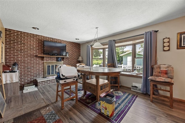 200 Drexel Dr SW, Cedar Rapids, IA 52404 - dining area featuring a textured ceiling, brick wall, wood finished floors, and a fireplace
