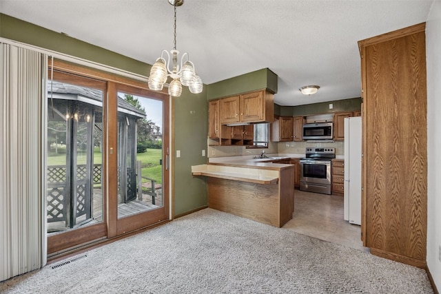 805 W 17th St, Vinton, IA 52349 - kitchen featuring appliances with stainless steel finishes, a peninsula, light countertops, a chandelier, and light colored carpet