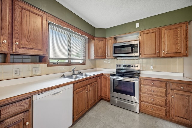 805 W 17th St, Vinton, IA 52349 - kitchen with appliances with stainless steel finishes, brown cabinets, backsplash, light countertops, and a textured ceiling