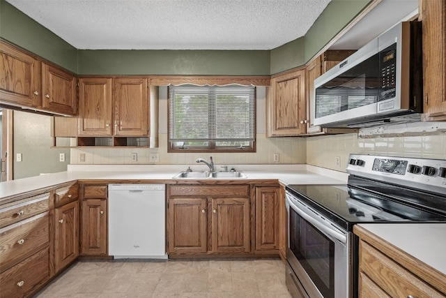 805 W 17th St, Vinton, IA 52349 - kitchen with stainless steel appliances, light countertops, brown cabinets, tasteful backsplash, and a textured ceiling