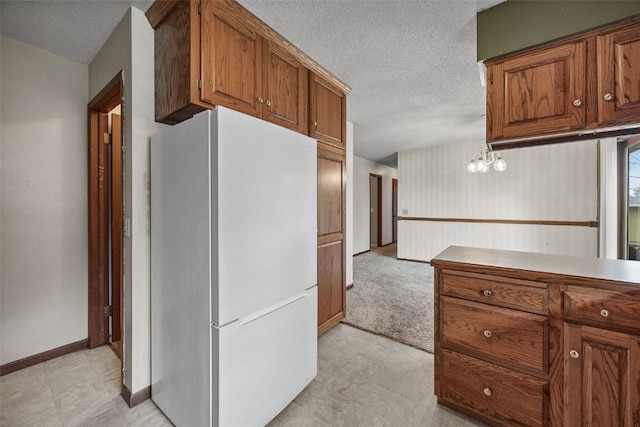 805 W 17th St, Vinton, IA 52349 - kitchen with freestanding refrigerator, brown cabinetry, a textured ceiling, light floors, and a chandelier