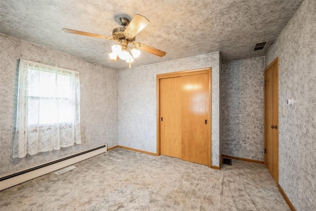 819 Valley St, Center Point, IA 52213 - unfurnished bedroom with a baseboard heating unit, carpet, ceiling fan, and a closet