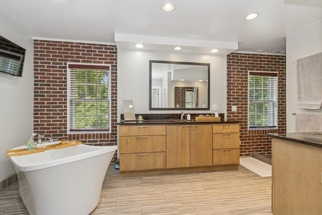 318 Ferson Ave, Iowa City, IA 52246 - bathroom with brick wall, vanity, a freestanding bath, and recessed lighting