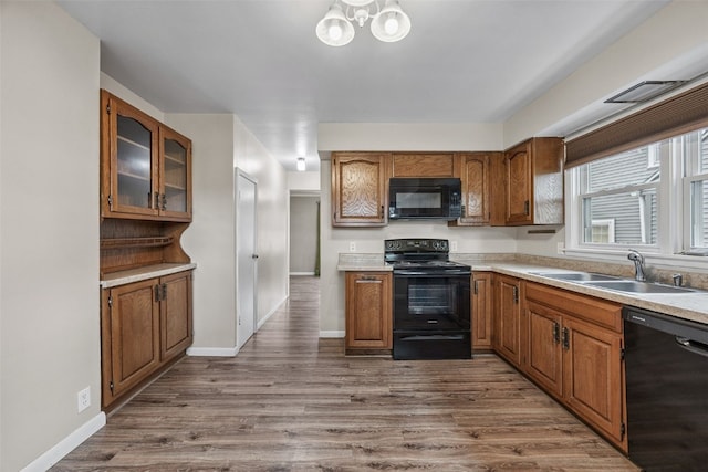 2539 Vernon Ct SE, Cedar Rapids, IA 52403 - kitchen with black appliances, brown cabinets, dark wood-style floors, glass insert cabinets, and light countertops