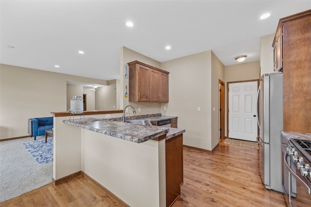 615 34th Ave, Marion, IA 52302 - kitchen featuring a peninsula, appliances with stainless steel finishes, light wood-type flooring, brown cabinetry, and recessed lighting