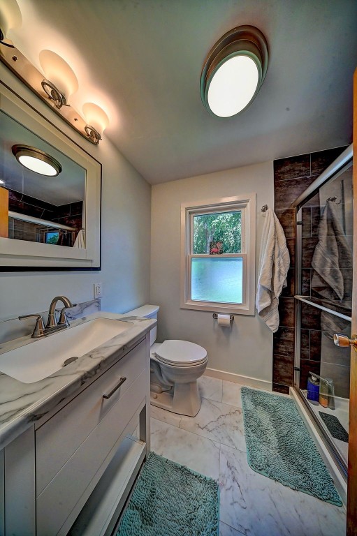 1175 28th St, Marion, IA 52302 - bathroom with marble look tile flooring, a shower stall, and vanity
