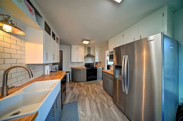 1175 28th St, Marion, IA 52302 - kitchen featuring stainless steel appliances, wall chimney range hood, tasteful backsplash, white cabinets, and butcher block counters