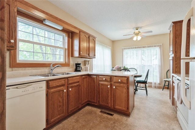 4555 Westchester Dr NE Unit B, Cedar Rapids, IA 52402 - kitchen with white appliances, a peninsula, brown cabinets, light countertops, and ceiling fan
