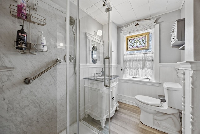 1860 E Ave NW, Cedar Rapids, IA 52405 - bathroom with a stall shower, vanity, a wainscoted wall, wood finished floors, and a decorative wall