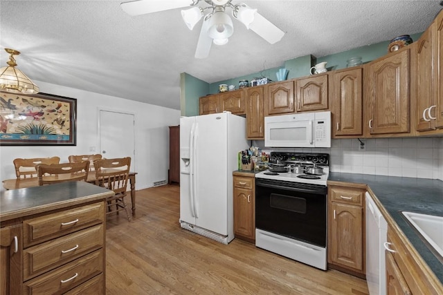 6613 Devonshire Dr NE, Cedar Rapids, IA 52402 - kitchen featuring white appliances, light wood-style floors, dark countertops, a textured ceiling, and decorative backsplash