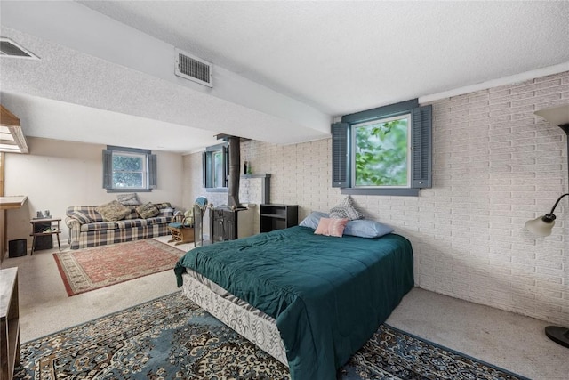 6613 Devonshire Dr NE, Cedar Rapids, IA 52402 - bedroom with brick wall, carpet flooring, a textured ceiling, a wood stove, and multiple windows