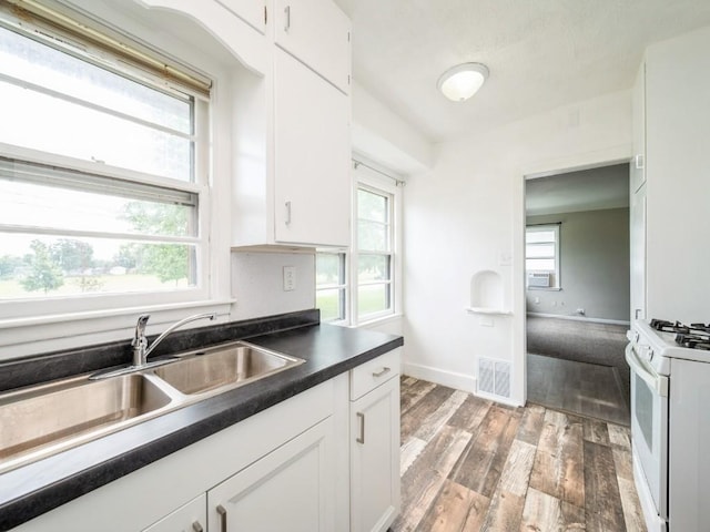 2408 J St SW, Cedar Rapids, IA 52404 - kitchen with white range with gas cooktop, wood finished floors, dark countertops, and white cabinets
