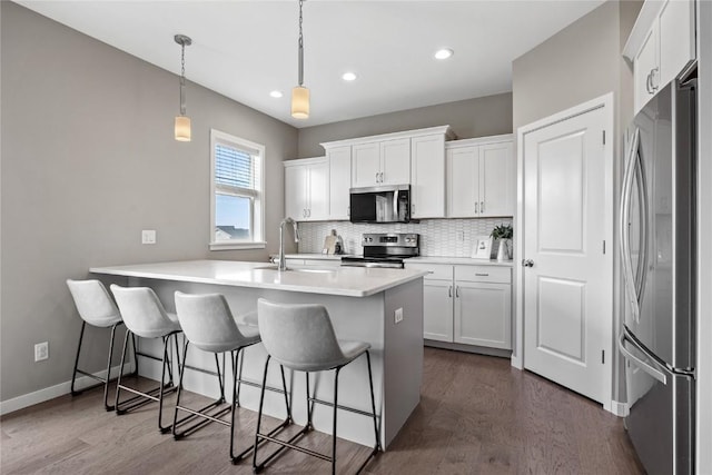 2455 Bridlewood Ct, Marion, IA 52302 - kitchen with appliances with stainless steel finishes, dark wood-style flooring, a kitchen breakfast bar, white cabinetry, and tasteful backsplash