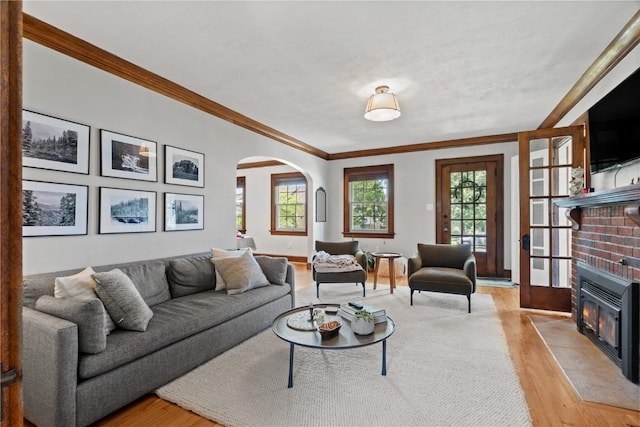2021 Bever Ave SE, Cedar Rapids, IA 52403 - living room featuring arched walkways, light wood-type flooring, crown molding, and a brick fireplace
