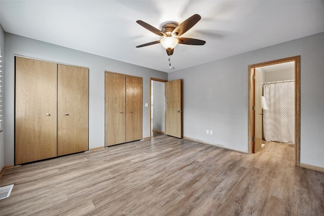 1458 Tower Ln NE Unit 12, Cedar Rapids, IA 52402 - unfurnished bedroom featuring multiple closets, light wood finished floors, ceiling fan, and ensuite bath
