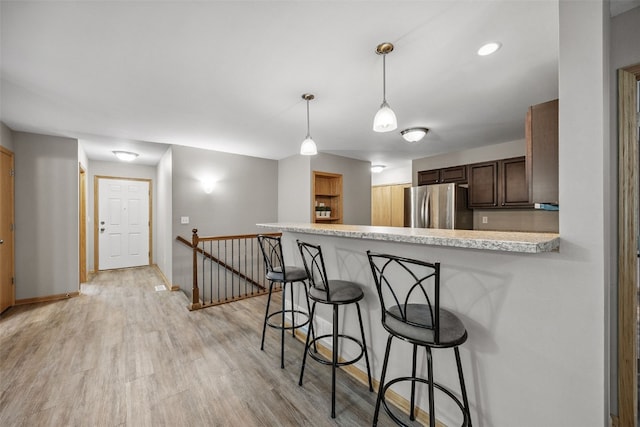 1458 Tower Ln NE Unit 12, Cedar Rapids, IA 52402 - kitchen with freestanding refrigerator, light countertops, a breakfast bar area, a peninsula, and decorative light fixtures