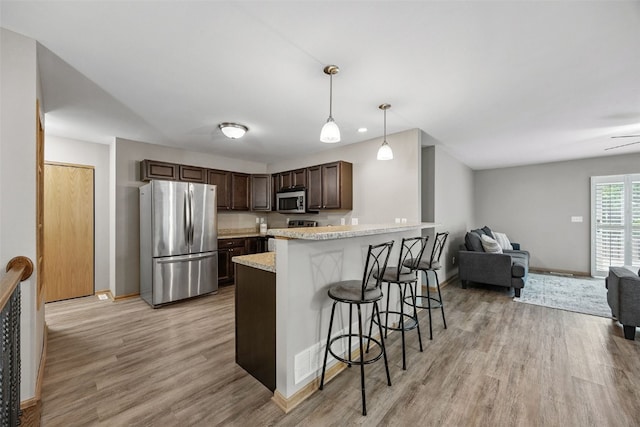 1458 Tower Ln NE Unit 12, Cedar Rapids, IA 52402 - kitchen with appliances with stainless steel finishes, light wood-style floors, dark brown cabinets, a peninsula, and a kitchen bar