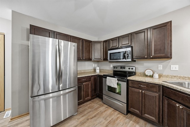 1458 Tower Ln NE Unit 12, Cedar Rapids, IA 52402 - kitchen featuring stainless steel appliances, dark brown cabinets, and light wood-style floors