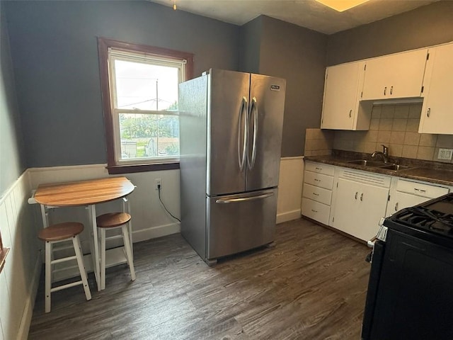 1839 K Ave NE, Cedar Rapids, IA 52402 - kitchen with freestanding refrigerator, black gas stove, white cabinetry, dark wood-style flooring, and wainscoting