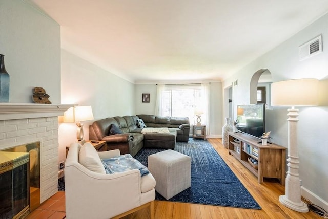 1935 1st Ave SW, Cedar Rapids, IA 52405 - living area featuring a brick fireplace, light wood-style flooring, and arched walkways