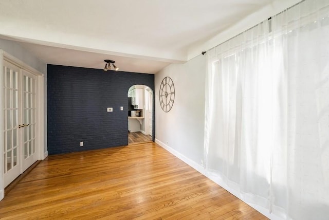 1935 1st Ave SW, Cedar Rapids, IA 52405 - spare room featuring arched walkways, light wood finished floors, brick wall, and french doors