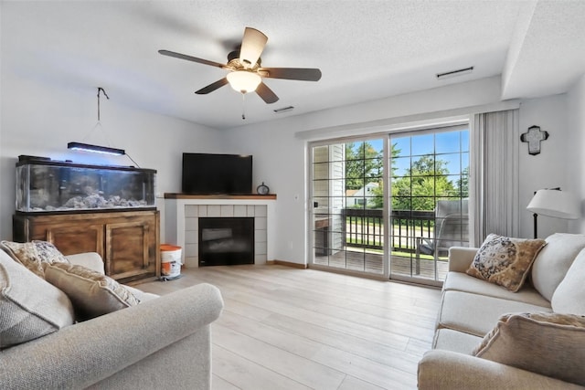3060 Wilson Ave SW Unit 7, Cedar Rapids, IA 52404 - living room with a ceiling fan, wood finished floors, a textured ceiling, and a tiled fireplace