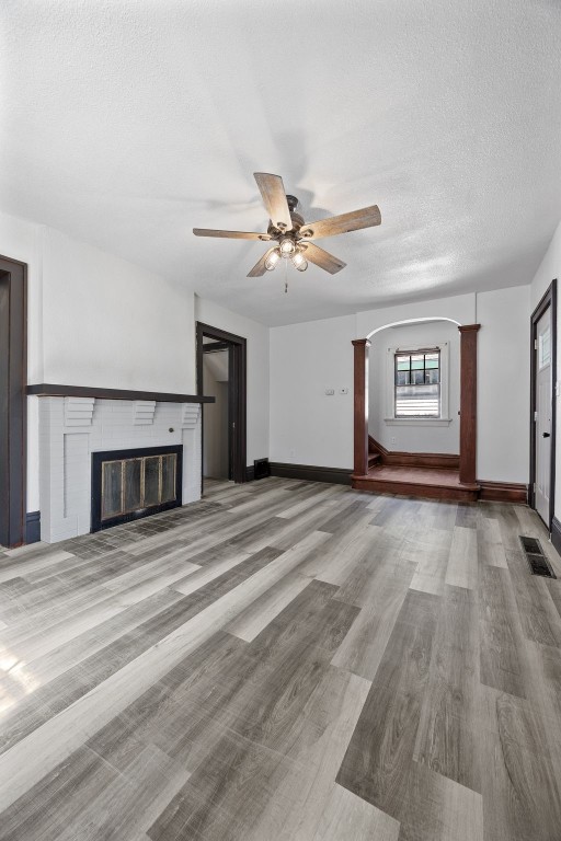 1818 Park Ave SE, Cedar Rapids, IA 52403 - unfurnished living room featuring a glass covered fireplace, a ceiling fan, a textured ceiling, and wood finished floors