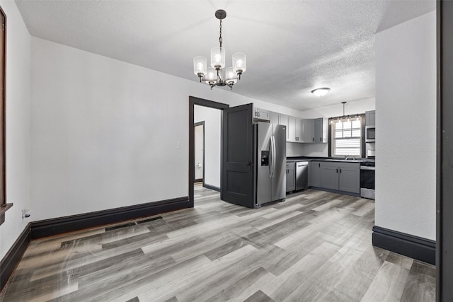 1818 Park Ave SE, Cedar Rapids, IA 52403 - kitchen with a chandelier, stainless steel appliances, light wood finished floors, gray cabinetry, and a textured ceiling
