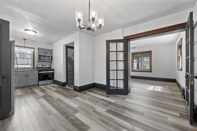 1818 Park Ave SE, Cedar Rapids, IA 52403 - unfurnished dining area with light wood-style flooring, healthy amount of natural light, a chandelier, and a textured ceiling